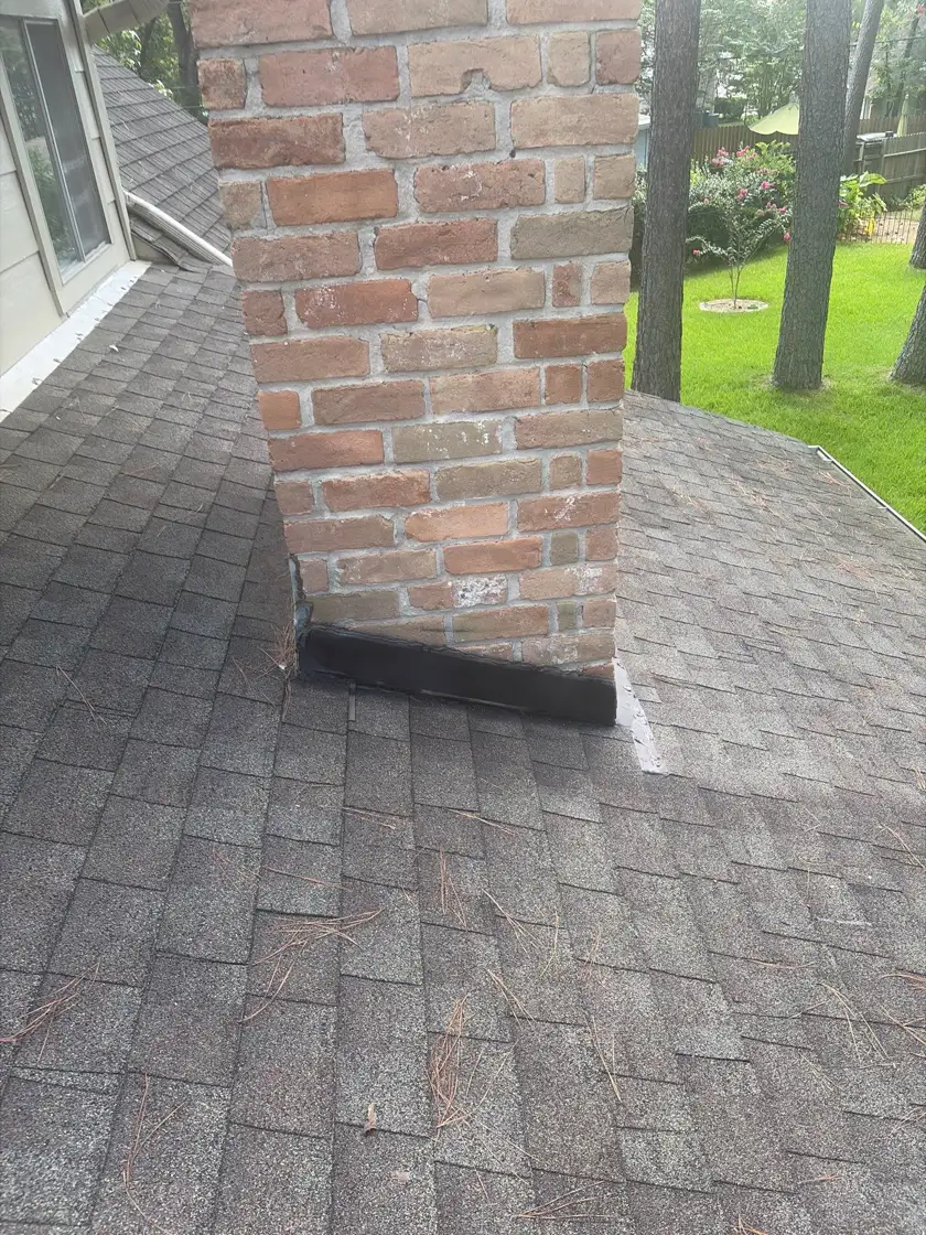 New chimney flashing sealed against brick on a gray shingle roof in Houston