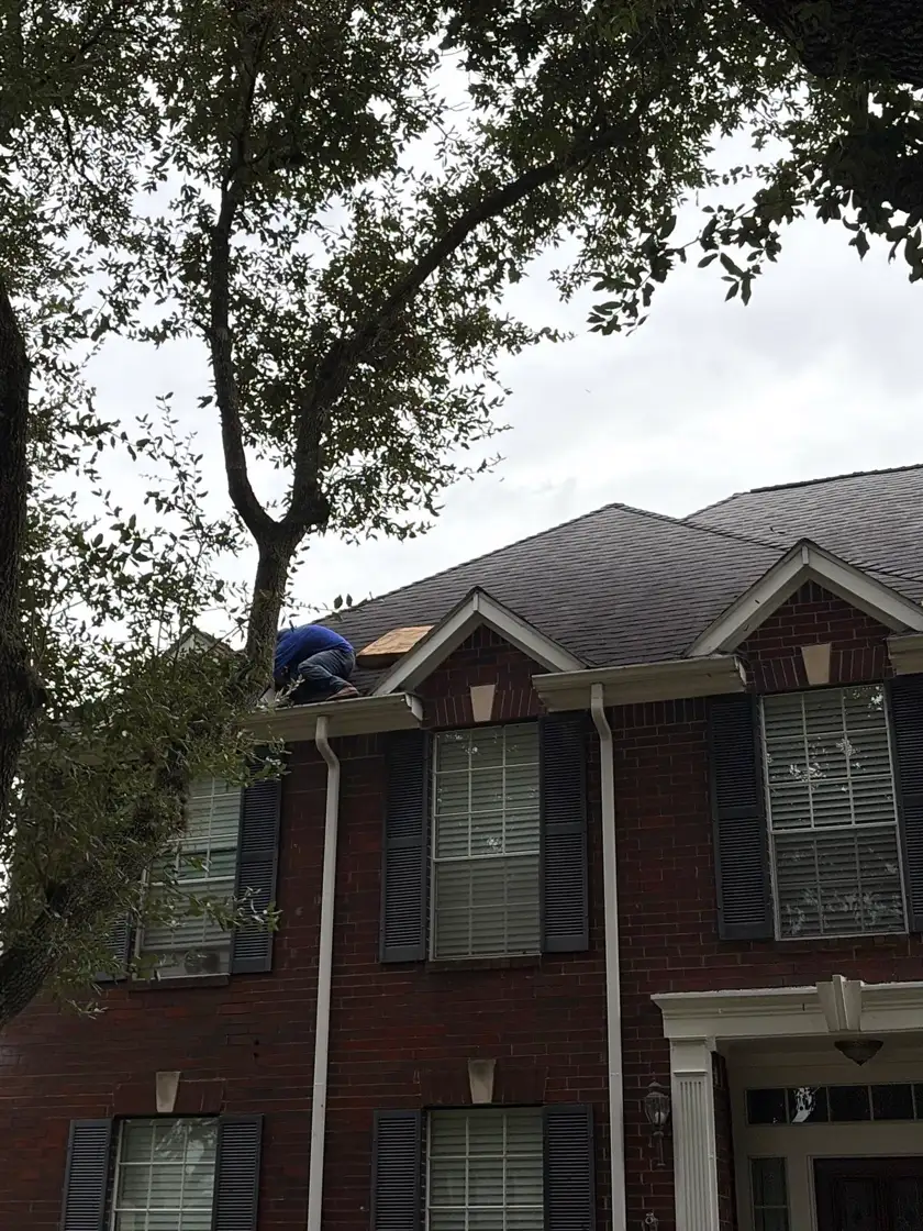 Roofing crew working on the roof of a brick home in Sugar Land, TX